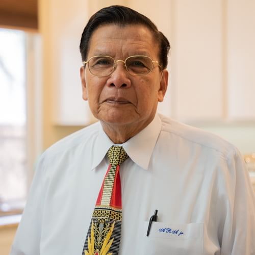 Dr. Amable Aguiluz Jr, a distinguished gentleman with glasses, wearing a white shirt and patterned tie.